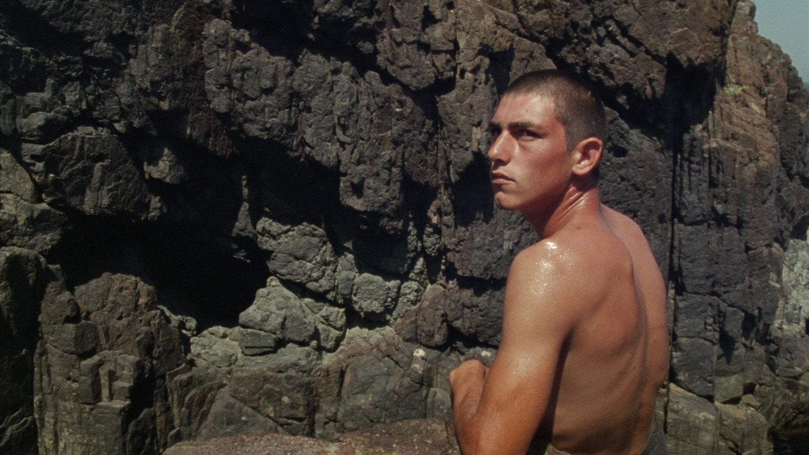 Man looking into the distance against backdrop of a rocky wall
