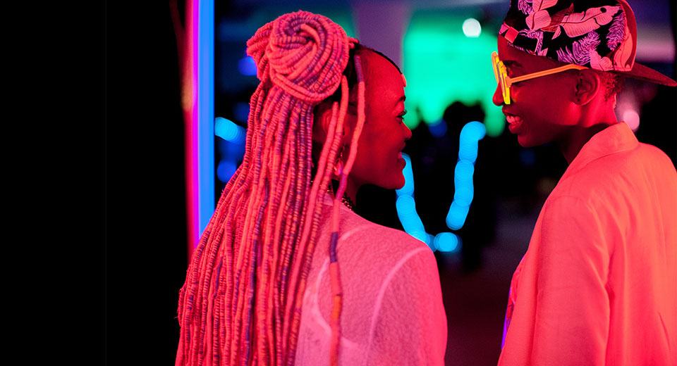 Neon-lit scene from Rafiki of the two lead female characters in a club
